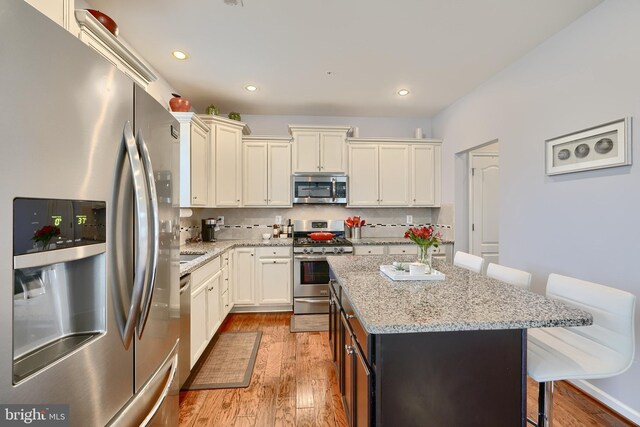 kitchen with stainless steel appliances, light hardwood / wood-style floors, a center island, and a breakfast bar area