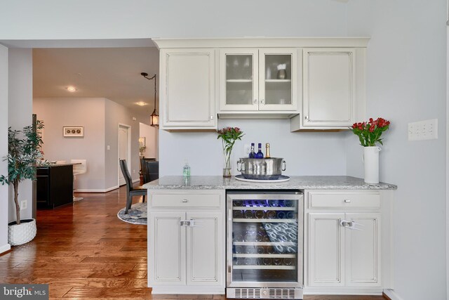 bar featuring light stone counters, wine cooler, dark wood-type flooring, and white cabinetry