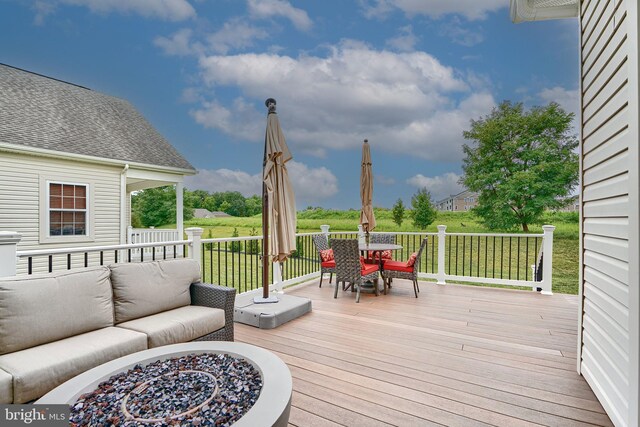 wooden deck with a fire pit and a lawn