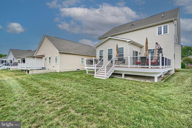 rear view of house featuring a deck and a lawn