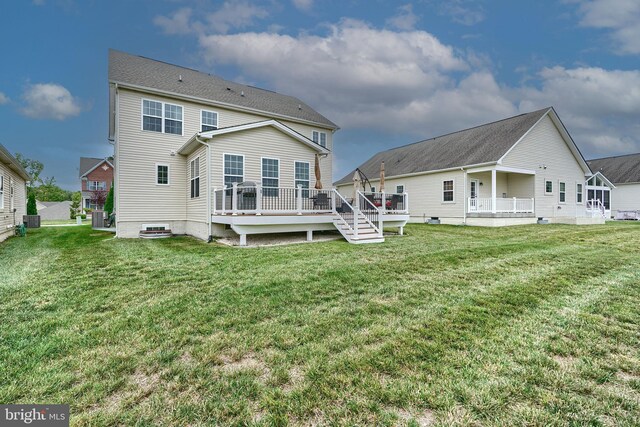 back of property featuring a wooden deck and a lawn