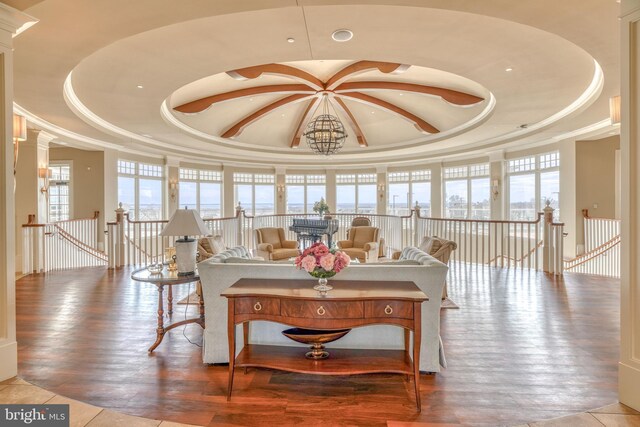 living room with an inviting chandelier, a tray ceiling, decorative columns, and hardwood / wood-style floors