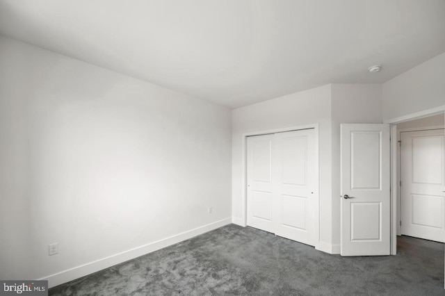 unfurnished bedroom featuring a closet and dark colored carpet