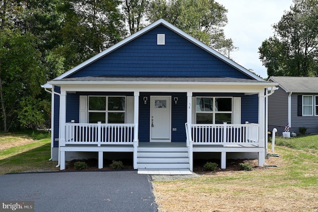 bungalow-style home featuring covered porch and a front yard