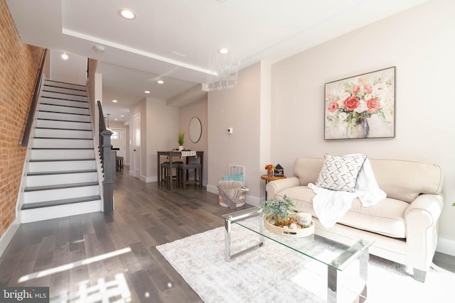 living room with brick wall and dark hardwood / wood-style floors