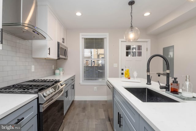 kitchen featuring tasteful backsplash, stainless steel appliances, sink, hardwood / wood-style flooring, and wall chimney exhaust hood