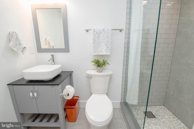 bathroom with tiled shower, vanity, tile patterned floors, and toilet