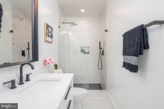 bathroom featuring tile patterned floors, vanity, a tile shower, and toilet