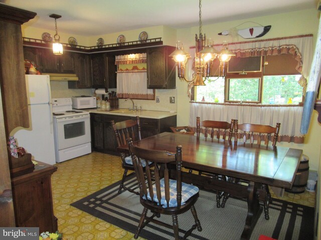 kitchen with white appliances, dark brown cabinetry, sink, pendant lighting, and a chandelier