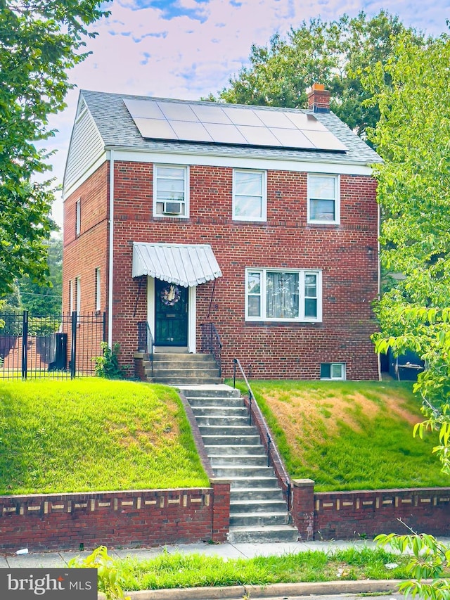 view of front of property featuring a lawn and solar panels