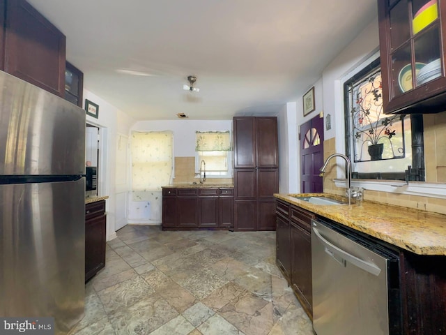 kitchen with light stone countertops, sink, and stainless steel appliances