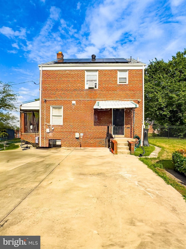 rear view of property featuring solar panels