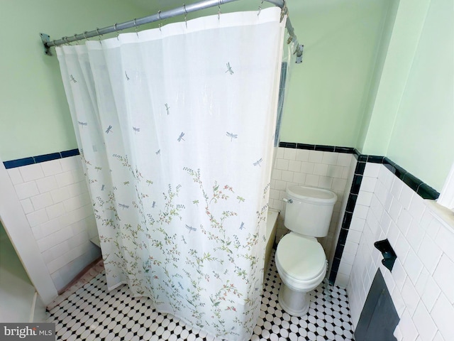 bathroom with toilet, tile walls, and tile patterned floors