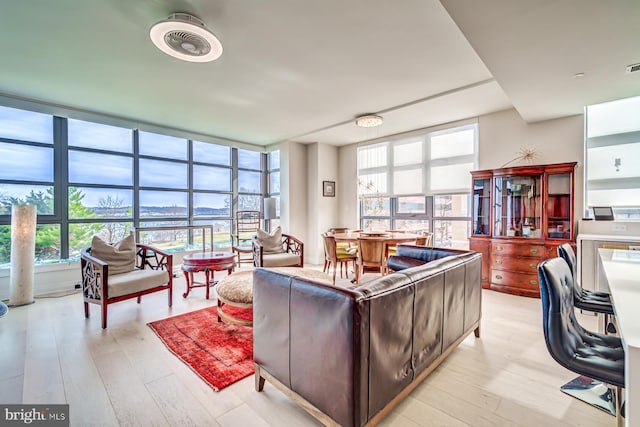 living room featuring light wood-type flooring and a wall of windows