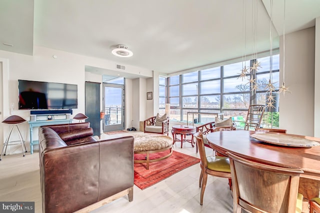 living room with plenty of natural light, light hardwood / wood-style flooring, and a wall of windows