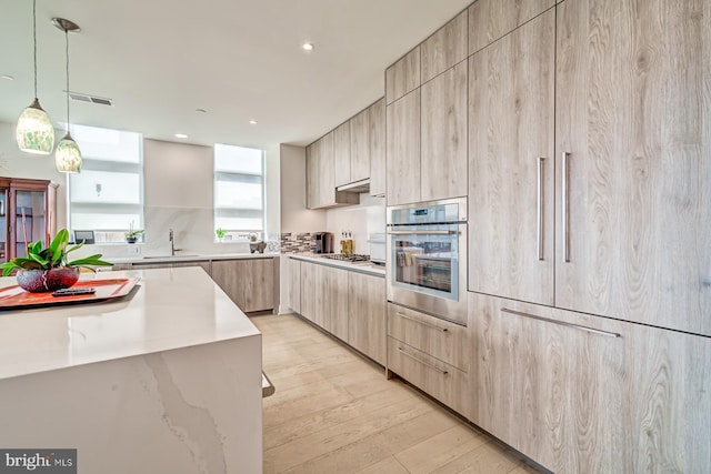 kitchen featuring pendant lighting, sink, stainless steel appliances, and light brown cabinetry