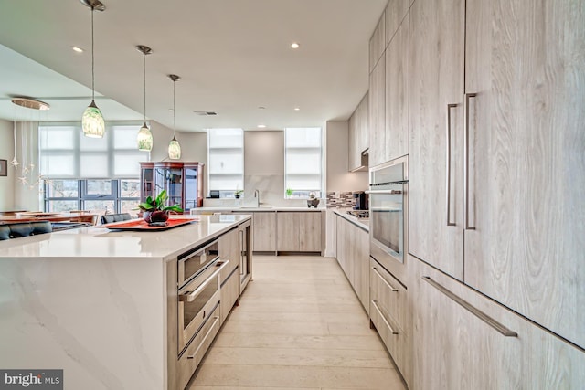 kitchen with a kitchen island, a healthy amount of sunlight, sink, decorative light fixtures, and oven