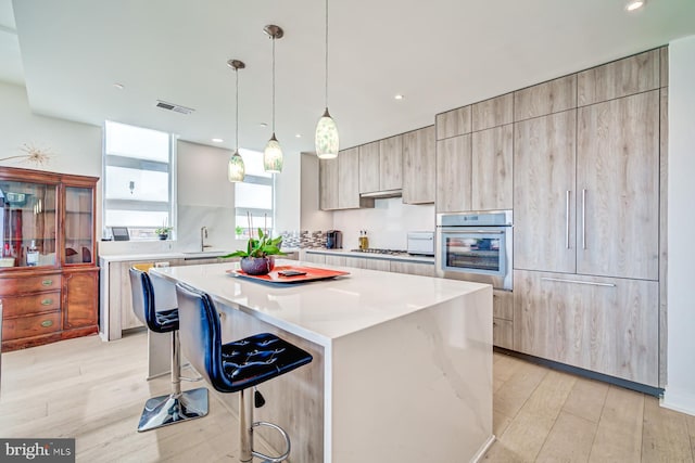 kitchen with appliances with stainless steel finishes, sink, decorative light fixtures, a kitchen island, and a breakfast bar area