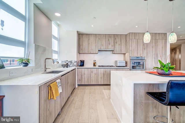 kitchen featuring sink, hanging light fixtures, backsplash, oven, and a kitchen bar