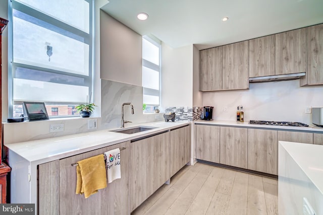 kitchen featuring tasteful backsplash, white gas cooktop, extractor fan, sink, and light hardwood / wood-style flooring