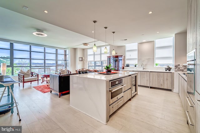 kitchen featuring a center island, a wall of windows, oven, pendant lighting, and light wood-type flooring