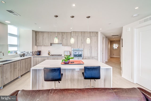 kitchen with a center island, decorative light fixtures, wall oven, and a breakfast bar area