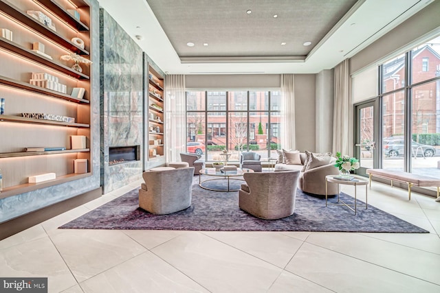 interior space with tile patterned flooring, a raised ceiling, built in features, and a fireplace