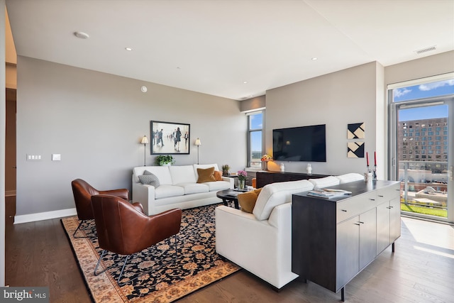 living room featuring dark wood-type flooring and a wealth of natural light