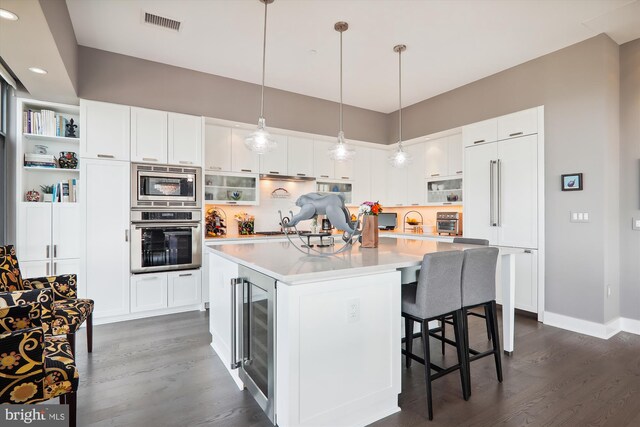 kitchen with white cabinetry, a center island, built in appliances, and wine cooler