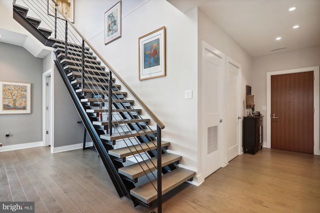 staircase with a towering ceiling and hardwood / wood-style floors