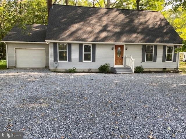 new england style home featuring a garage, crawl space, roof with shingles, and gravel driveway