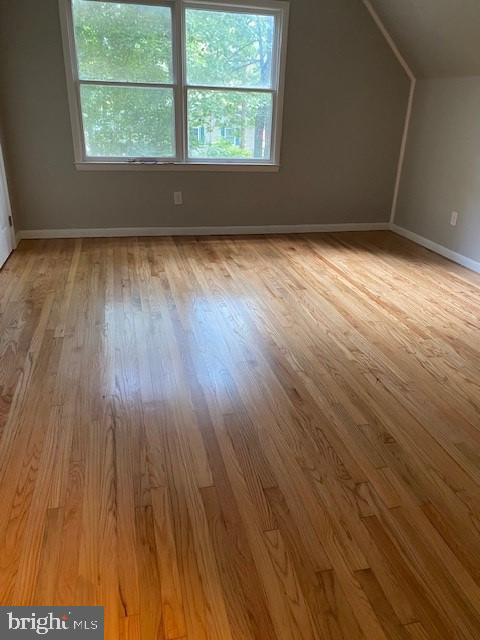 additional living space with a healthy amount of sunlight, vaulted ceiling, and wood finished floors