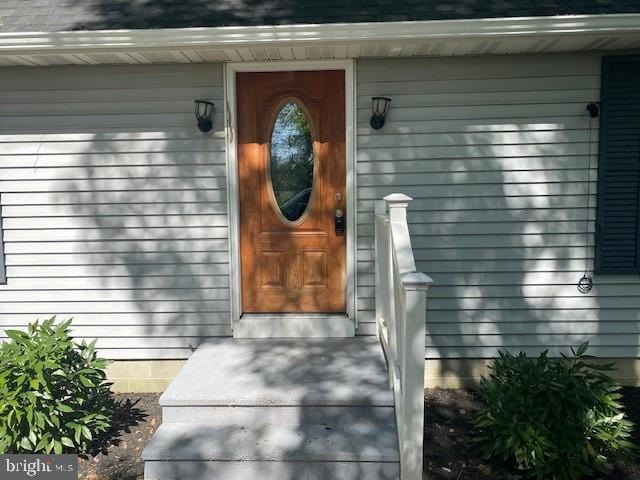 property entrance featuring roof with shingles