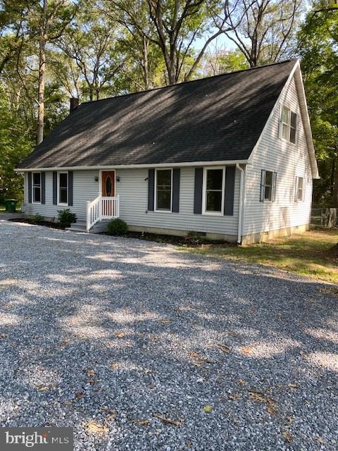 view of front of property featuring crawl space, a chimney, and gravel driveway