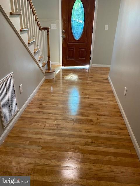 foyer with baseboards, visible vents, stairway, and light wood finished floors