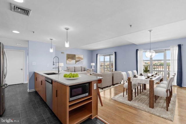 kitchen with decorative light fixtures, sink, a center island with sink, and stainless steel appliances