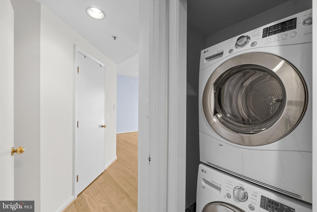 laundry room with light hardwood / wood-style floors and stacked washer / dryer