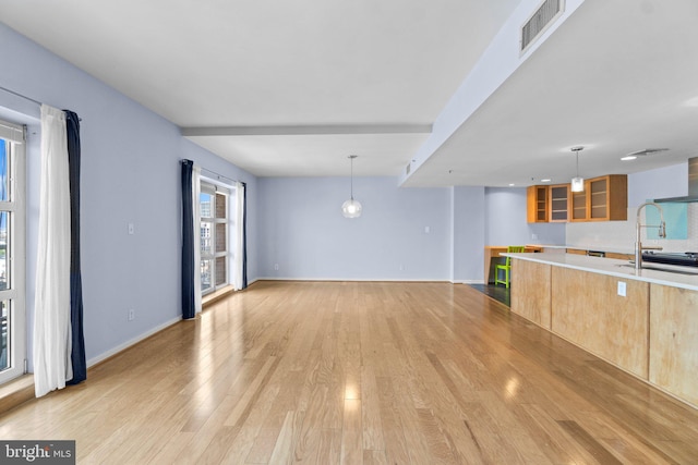 kitchen featuring light wood-type flooring, hanging light fixtures, and sink