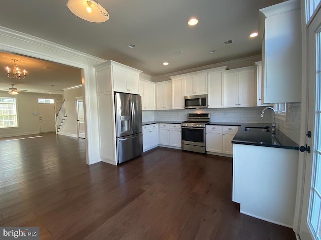 kitchen featuring white cabinets, sink, decorative backsplash, appliances with stainless steel finishes, and decorative light fixtures