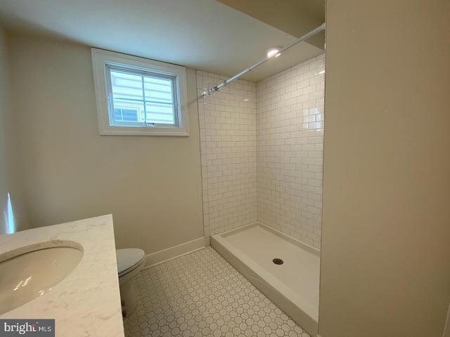 bathroom with tile patterned flooring, a tile shower, vanity, and toilet