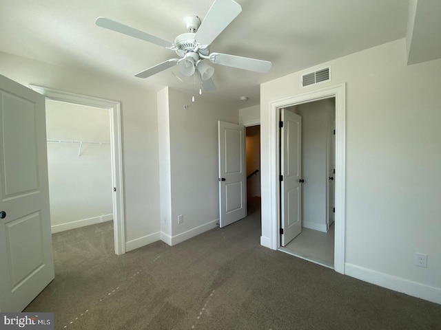 unfurnished bedroom featuring carpet flooring, ceiling fan, a spacious closet, and a closet