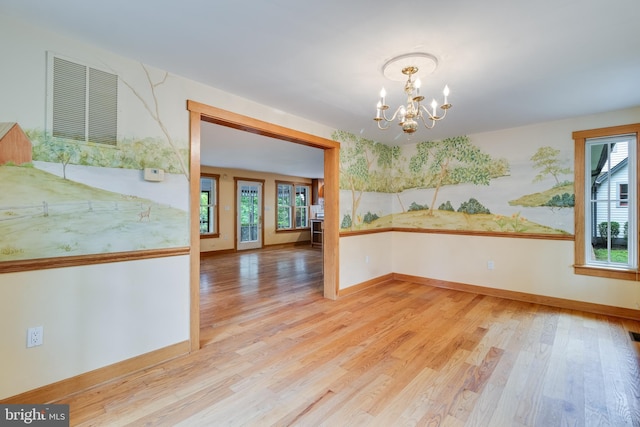 unfurnished dining area with a chandelier and light hardwood / wood-style floors