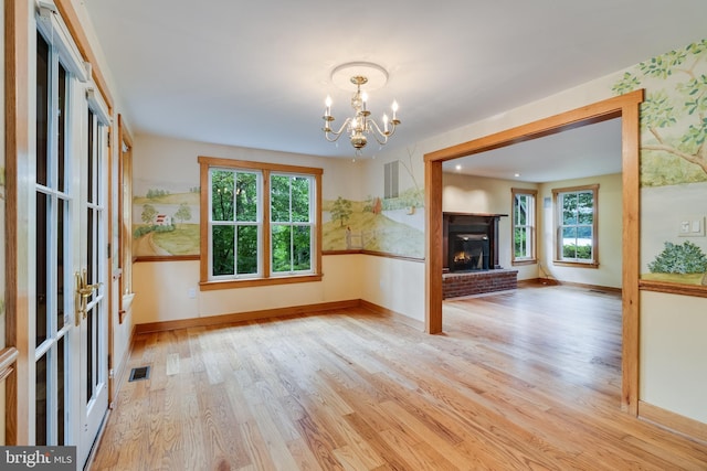 interior space featuring a brick fireplace, light hardwood / wood-style flooring, and a notable chandelier