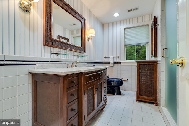 bathroom featuring tile patterned floors, vanity, tile walls, and toilet