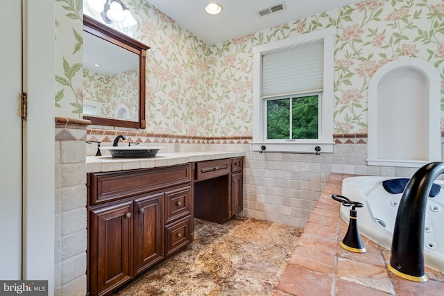 bathroom with vanity, a bath, and tile walls