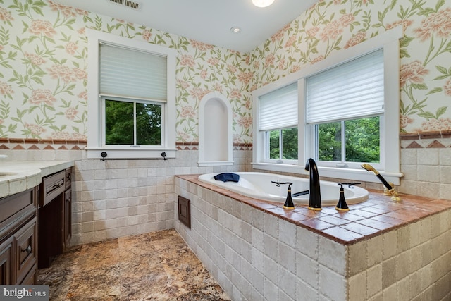 bathroom with vanity and tiled tub