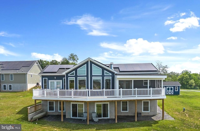 back of house with solar panels, a yard, and a deck