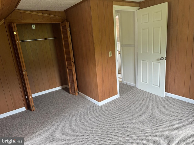 unfurnished bedroom featuring dark colored carpet and wooden walls