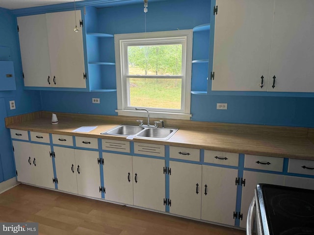 kitchen with white cabinets, stove, light hardwood / wood-style floors, and sink