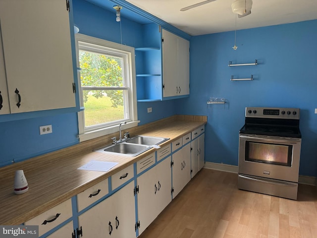 kitchen featuring stainless steel electric stove, sink, white cabinets, and light wood-type flooring